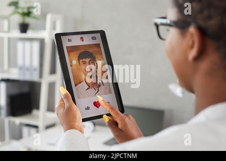 Femme utilise une tablette numérique et aime la photo d'un jeune homme sur une application de rencontres en ligne ou un site Web Banque D'Images