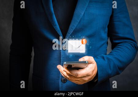 Homme d'affaires tenant un téléphone portable avec une icône de lettre virtuelle pour le concept d'alerte de notification d'application. Main d'homme d'affaires utilisant un smartphone pour la messagerie avec Banque D'Images