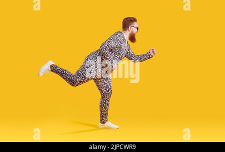 Drôle excentrique gros homme dans les vêtements avec l'imprimé léopard bertant autour sur fond jaune. Banque D'Images