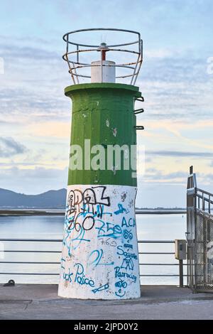 petit phare sur la jetée du port au crépuscule. Banque D'Images