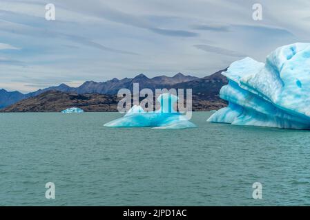 D'énormes blocs de glace flottent dans le lac Argentino sous un ciel nuageux Banque D'Images