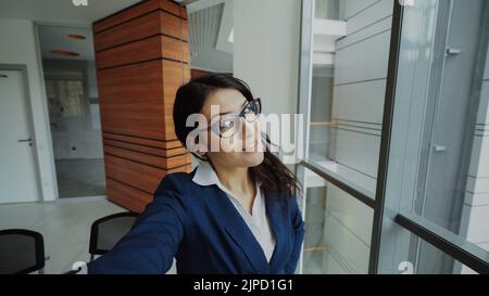 POV de la jeune femme d'affaires en costume prendre un selfie photo tenant un smartphone et s'amuser dans le bureau moderne à l'intérieur Banque D'Images