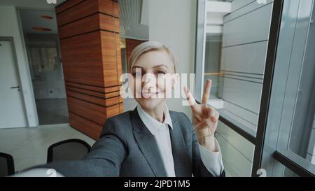 POV de la jeune femme d'affaires en costume prendre un selfie photo tenant un smartphone et s'amuser dans le bureau moderne à l'intérieur Banque D'Images