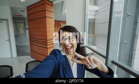 POV de la jeune femme d'affaires en costume prendre un selfie photo tenant un smartphone et s'amuser dans le bureau moderne à l'intérieur Banque D'Images