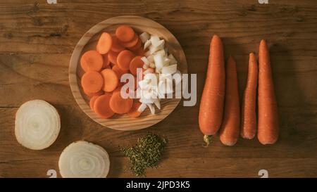 Maison encore vie avec des carottes et des oignons sur une table en bois et sur une assiette coupée en tranches, origan et épices Banque D'Images
