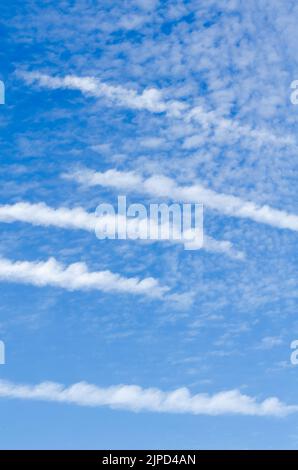 Les sentiers de condensation de l'avion et les nuages dans le ciel bleu Banque D'Images