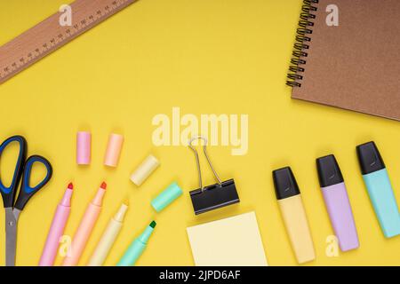 Carnet, ciseaux, crayons de couleur, règle, papier note et pince. Retour à l'école. Arrière-plan jaune isolé Banque D'Images