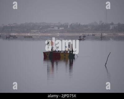 Quelques touristes africains naviguent avec aguide dans un petit bateau sur le lac rose, Dakar. Banque D'Images