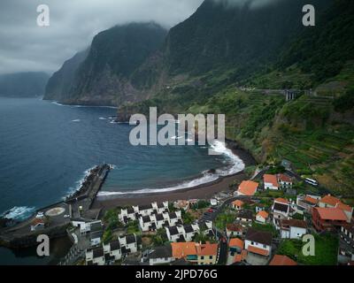 Une photo aérienne de la magnifique plage noire de Seixal au-dessus du village avec des nuages épiques entre les montagnes Banque D'Images