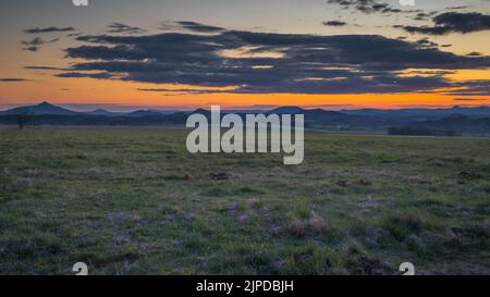 Coucher de soleil romantique sur un champ dans le nord de la Bohême. Le ciel est calme et avec peu de nuages et de soleil au-dessus de l'horizon. Banque D'Images