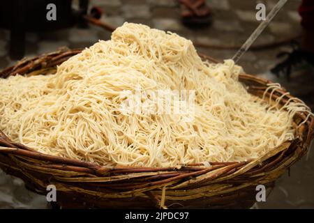 Chinois Schezwan également appelé Szechwan Veg Hakka Noodles Chowmin ou Indian Veg Chow Mein être rincé dans l'eau dans le panier de bambou. Style Dhaba Banque D'Images