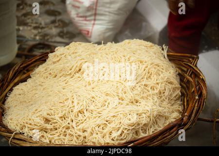 Chinois Schezwan également appelé Szechwan Veg Hakka Noodles Chowmin ou Indian Veg Chow Mein être rincé dans l'eau dans le panier de bambou. Style Dhaba Banque D'Images