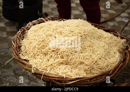 Chinois Schezwan également appelé Szechwan Veg Hakka Noodles Chowmin ou Indian Veg Chow Mein être rincé dans l'eau dans le panier de bambou. Style Dhaba Banque D'Images