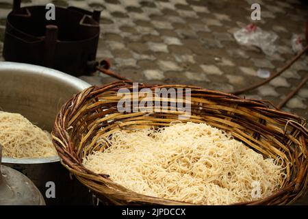 Chinois Schezwan également appelé Szechwan Veg Hakka Noodles Chowmin ou Indian Veg Chow Mein être rincé dans l'eau dans le panier de bambou. Style Dhaba Banque D'Images