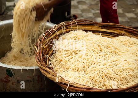 Chinois Schezwan également appelé Szechwan Veg Hakka Noodles Chowmin ou Indian Veg Chow Mein être rincé dans l'eau dans le panier de bambou. Dhaba style Bul Banque D'Images