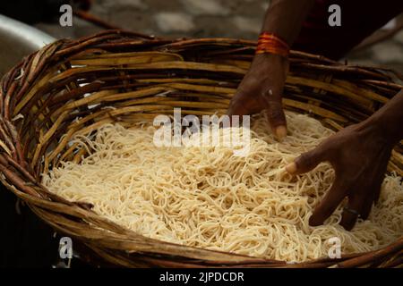 Chinois Schezwan également appelé Szechwan Veg Hakka Noodles Chowmin ou Indian Veg Chow Mein être rincé dans l'eau dans le panier de bambou. Dhaba style Bul Banque D'Images