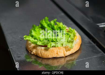 gros plan sur le début de la préparation d'un hamburger colombien, dans un kiosque à fast-food situé dans la rue. pain et laitue sur une table métallique. Banque D'Images