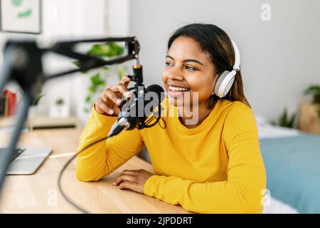 Jeune femme ethnique enregistrant un podcast radio à partir d'un studio à domicile Banque D'Images