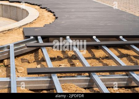 Un cadre est fait avec des poutres en fer sur le sol, et le bois synthétique est posé sur lui pour faire une route. Banque D'Images