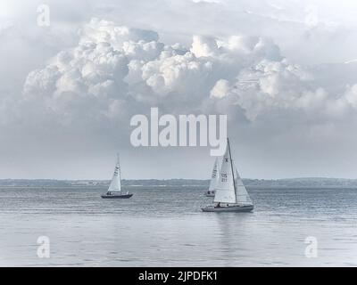 Calme après l'orage, la vue sur le solent jusqu'à l'orage au loin, tandis que les bateaux à voile traversent l'eau calme. Banque D'Images