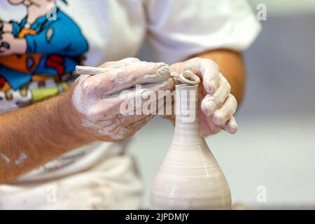 Un potier est montré façonnant un vase ou un vaisseau à partir d'argile fraîche humide. Il tond le haut du vaisseau avec un couteau pendant qu'il tourne sur son plateau tournant Banque D'Images