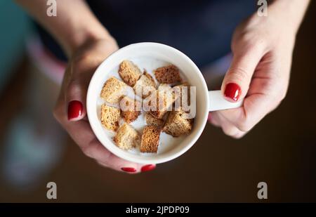 Les femmes tiennent le yogourt au lait avec des craquelins dans une tasse. Dessert maison appétissant Banque D'Images