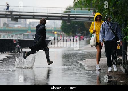 Les gens qui marchent sous la pluie à Londres. Après des semaines de temps marécageux, qui a causé la sécheresse et laissé des terres parcelées, l'avertissement d'orage jaune du met Office prévoit des pluies torrentielles et des orages qui pourraient frapper des parties de l'Angleterre et du pays de Galles. Date de la photo: Mercredi 17 août 2022. Banque D'Images