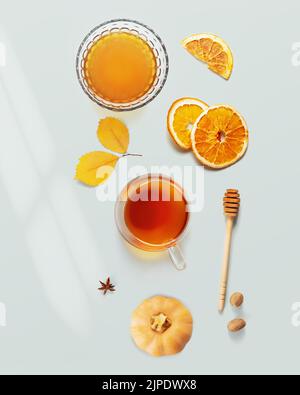 Nourriture d'automne. Tisane, miel, oranges sèches et épices sur fond bleu avec feuilles d'automne. Aliments immunisés, repas chaleureux. Pose à plat Banque D'Images