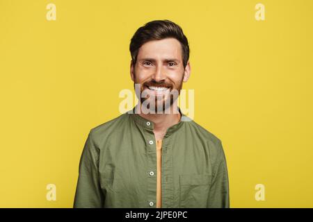 Portrait d'un homme heureux d'âge moyen posant et souriant à l'appareil photo sur fond jaune de studio, espace de copie Banque D'Images