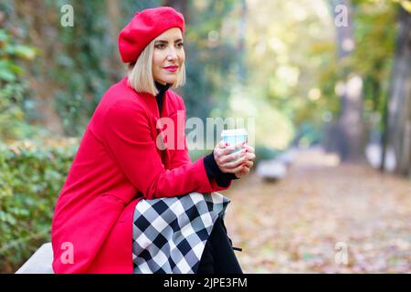 Femme élégante avec boisson chaude à emporter dans l'allée Banque D'Images