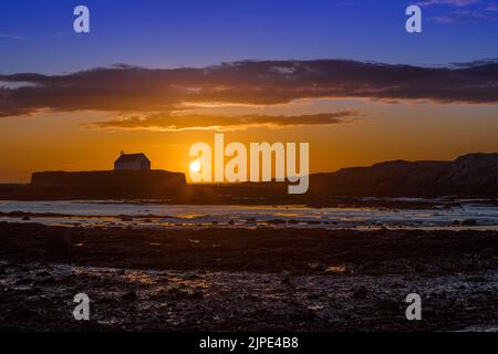 L'église St Cwyfan, connue sous le nom d'église dans la mer, au coucher du soleil à Anglesey, dans le nord du pays de Galles. Banque D'Images