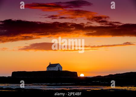 L'église St Cwyfan, connue sous le nom d'église dans la mer, au coucher du soleil à Anglesey, dans le nord du pays de Galles. Banque D'Images