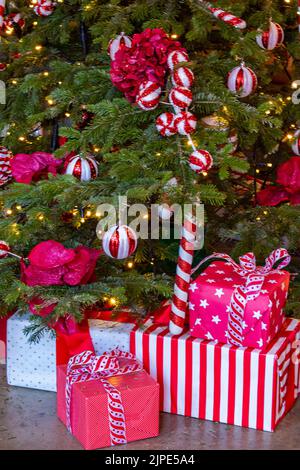 des cadeaux de noël sous l'arbre de noël pendant la saison des fêtes, des papiers d'emballage et des décorations de noël aux couleurs vives. Banque D'Images