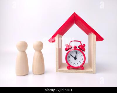 Poupée en bois des figures d'un couple, d'un réveil et d'une maison de jouets sur fond blanc Banque D'Images