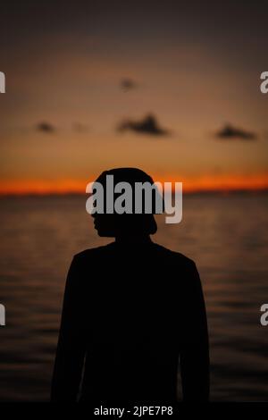 Une photo verticale de la silhouette d'une personne contre le ciel au coucher du soleil. Banque D'Images