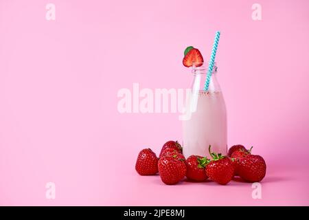 Smoothie aux fraises ou milkshake dans un pot en verre avec baies sur fond rose. Boisson d'été saine Banque D'Images