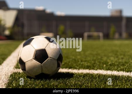 ballon de football blanc et noir sur fond d'herbe verte et de stade. idée de paris sportifs. Banque D'Images