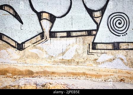 Gros plan d'une partie du graffiti peint sur un mur externe rugueux avec une partie du pavé Banque D'Images