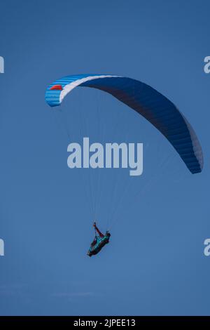Angle vertical bas d'un parachutiste volant haut dans le ciel bleu Banque D'Images