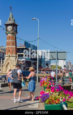 La tour de l'horloge près du défilé sud avec des foules de personnes profitant des commodités pendant le temps ensoleillé à Skegness Banque D'Images