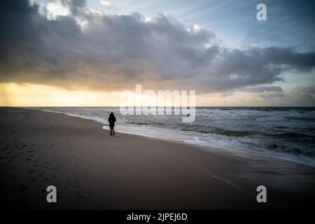 Une femme a marché seule à la plage pendant le coucher du soleil, Sylt, Allemagne. Banque D'Images