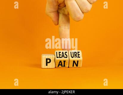 Symbole de douleur ou de plaisir. Concept mots douleur ou plaisir sur des cubes en bois. Main d'homme d'affaires. Belle table orange fond orange. Affaires et douleur Banque D'Images