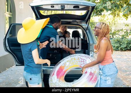 Des personnes diverses chargent leurs bagages dans le coffre, voyageant ensemble pendant les vacances. Les amis et la famille partent pour une aventure en bord de mer, le chargement de bagages et de valises, voyage en voiture. Banque D'Images