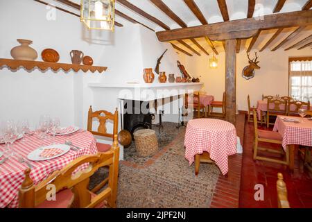 Salle à manger d'un restaurant de village de style rustique avec une grande cheminée avec foyer, poutres et colonnes en bois et détails décoratifs rustiques vintage Banque D'Images