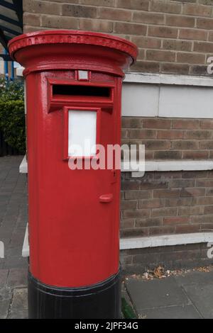 Gros plan d'une boîte aux lettres rouge rond rétro métal vintage sur un coin de mur de briques à Londres comme un concept pour les lettres de courrier et de contact Banque D'Images