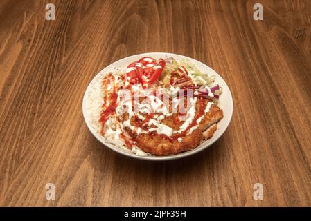 Filet de poulet pané avec sauces, riz basmati cuit et salade avec laitue et tranches de tomate Banque D'Images