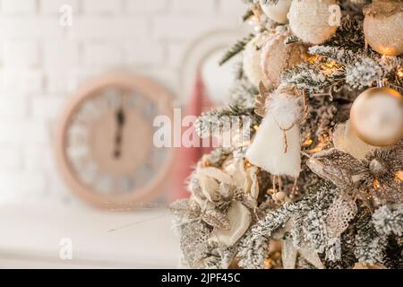 Un ange de Noël sur les branches d'un arbre de Noël sur le fond d'une horloge montrant 12.Célébration de la Saint-Sylvestre 2022 Banque D'Images