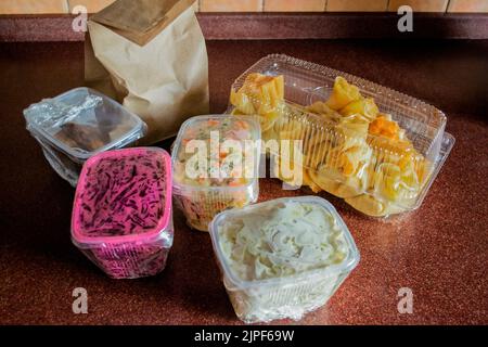 Livraison de nourriture du café: Un sac en papier avec des pâtisseries et des récipients en plastique avec salade russe, salade de betteraves, calmars et crêpes avec garniture. Banque D'Images