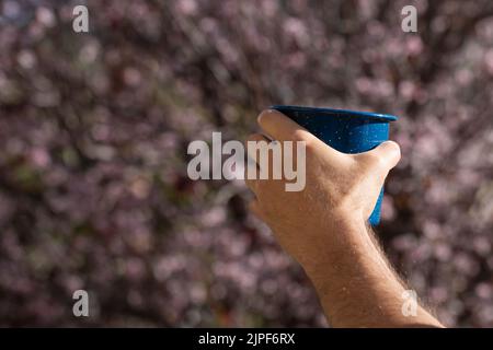 Main d'un homme tenant une tasse de café avec la nature dans le fond. Banque D'Images