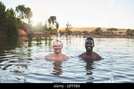 Vacances, amis et s'amuser tout en nageant dans un lac et en profitant de l'été. Portrait de gars heureux et divers souriant tout en appréciant l'eau et Banque D'Images